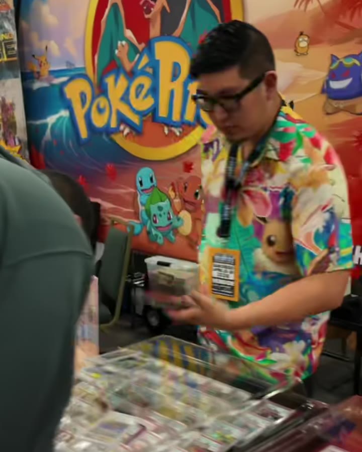 A vendor pulling cards from a Pokémon display case